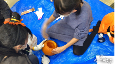 子どもがかぼちゃをくりぬいている様子